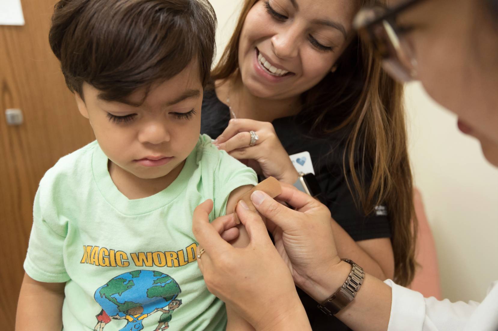 bambino che viene vaccinato in secondo piano una donna sorride