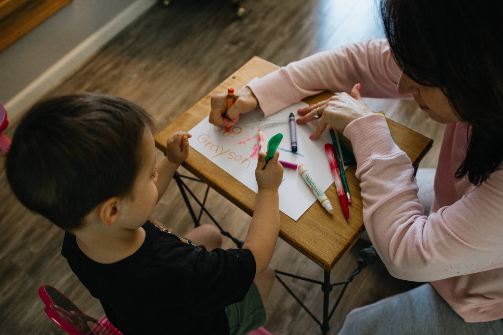 Bambino che impara a scrivere assistito da un'insegnante