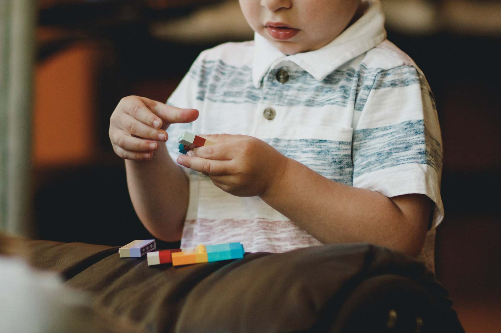 bambino con maglietta bianca che gioca con piccole costruzioni
