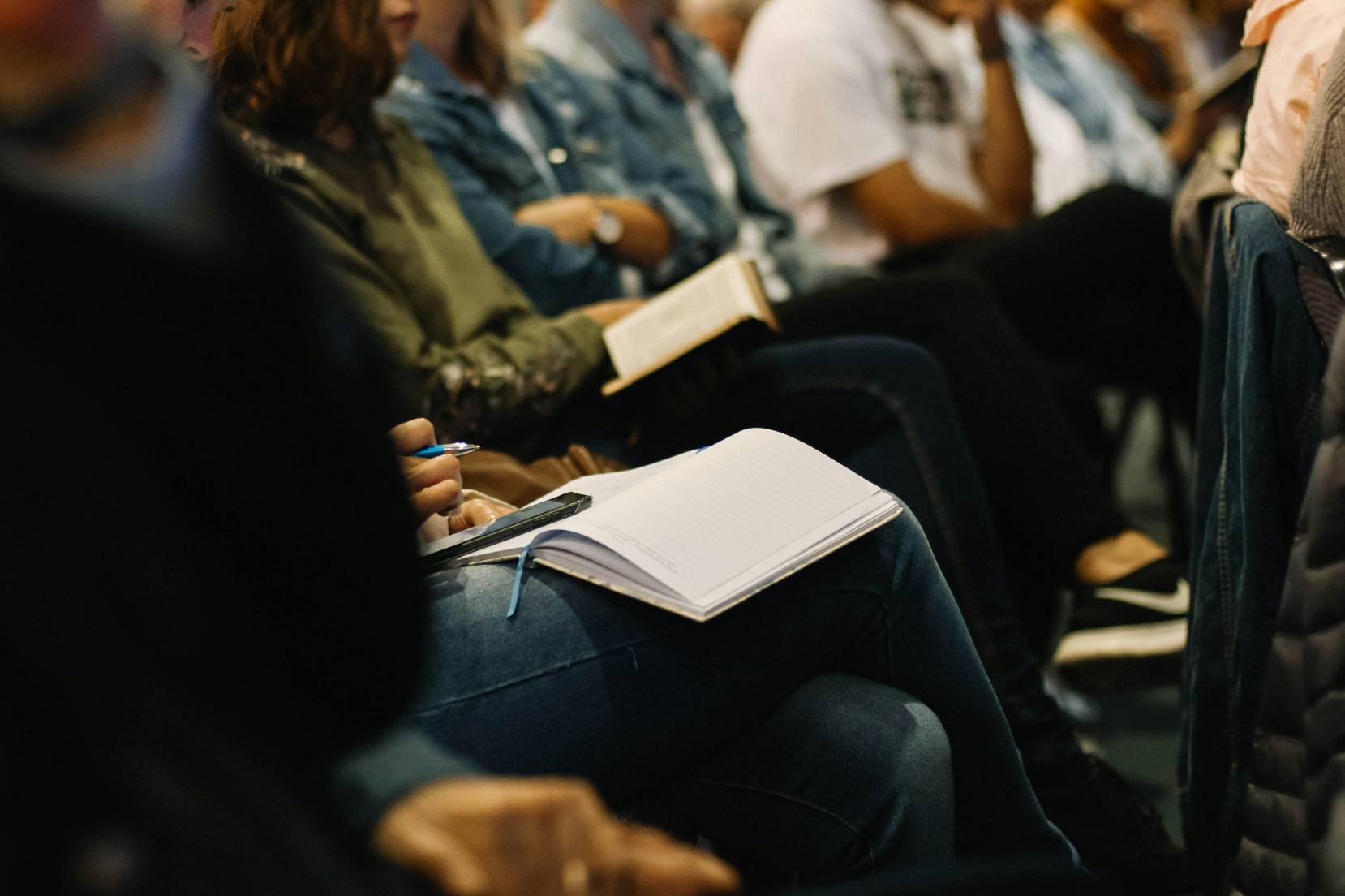 Gamde di persone sedute in fila che prendono appunti